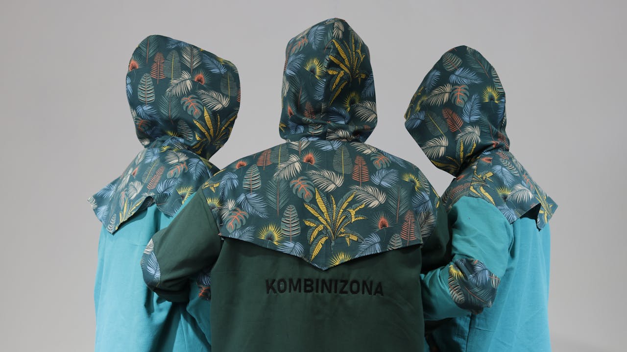 Three people in stylish floral patterned raincoats viewed from behind in a studio setting.